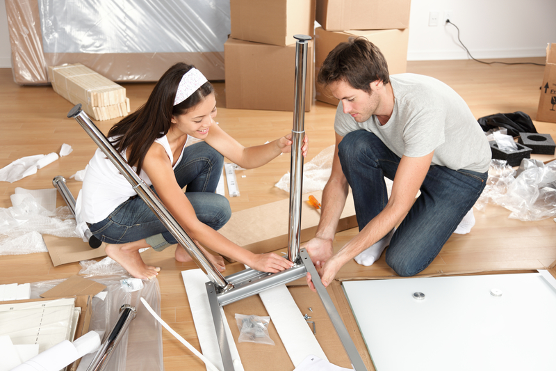 Couple moving in together assembling furniture table. Young interracial couple in new house or apartment home working together to assemble table. Asian woman, Caucasian man.