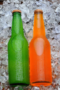 Two Soda Bottles on a Bed of Ice. Orange and Lemon Lime soft drinks with condensation in vertical format.