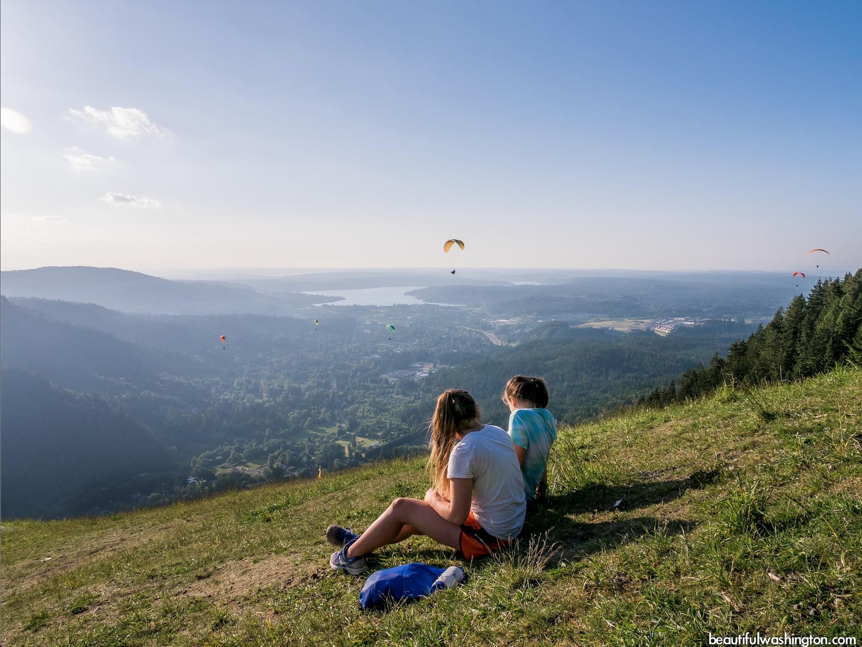 Two women watching paragliders